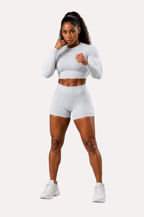 Woman in a white athletic outfit posing against a gray background